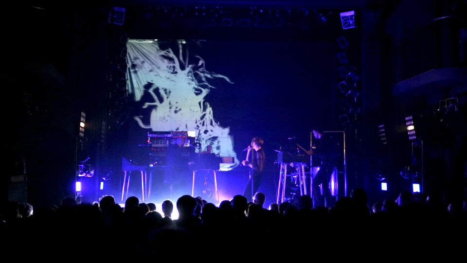 Hundreds on stage with »Bearer & Dancer« visual in background